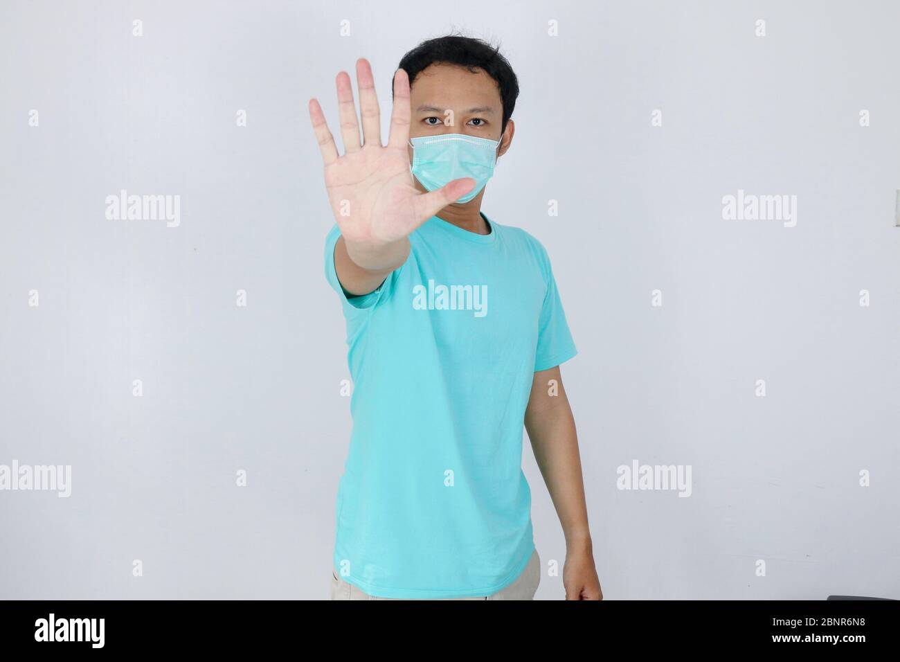 Junge asiatische Mann tragen hygienische Maske ist erschrocken oder Panik mit gesturing Stop Hand. Angst vor Coronavirus-Infektion oder Atemwegserkrankungen wie f Stockfoto