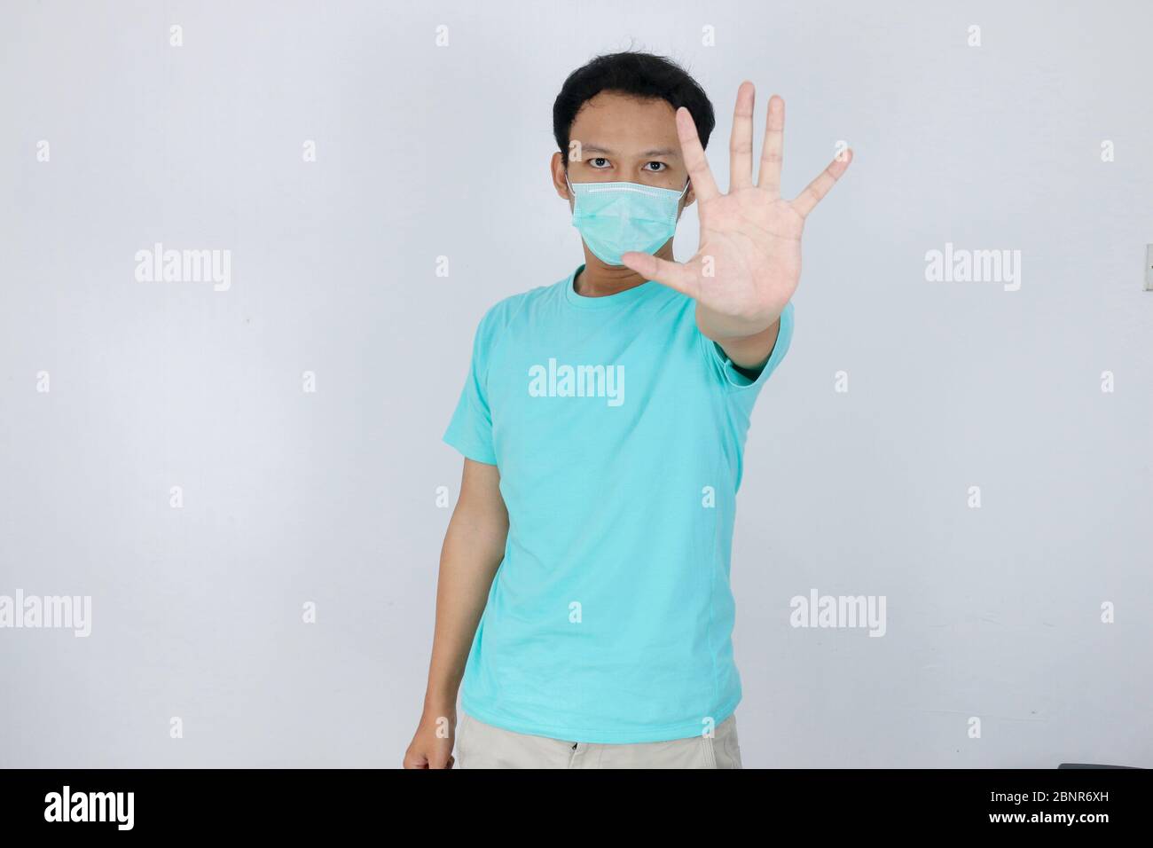Junge asiatische Mann tragen hygienische Maske ist erschrocken oder Panik mit gesturing Stop Hand. Angst vor Coronavirus-Infektion oder Atemwegserkrankungen wie f Stockfoto
