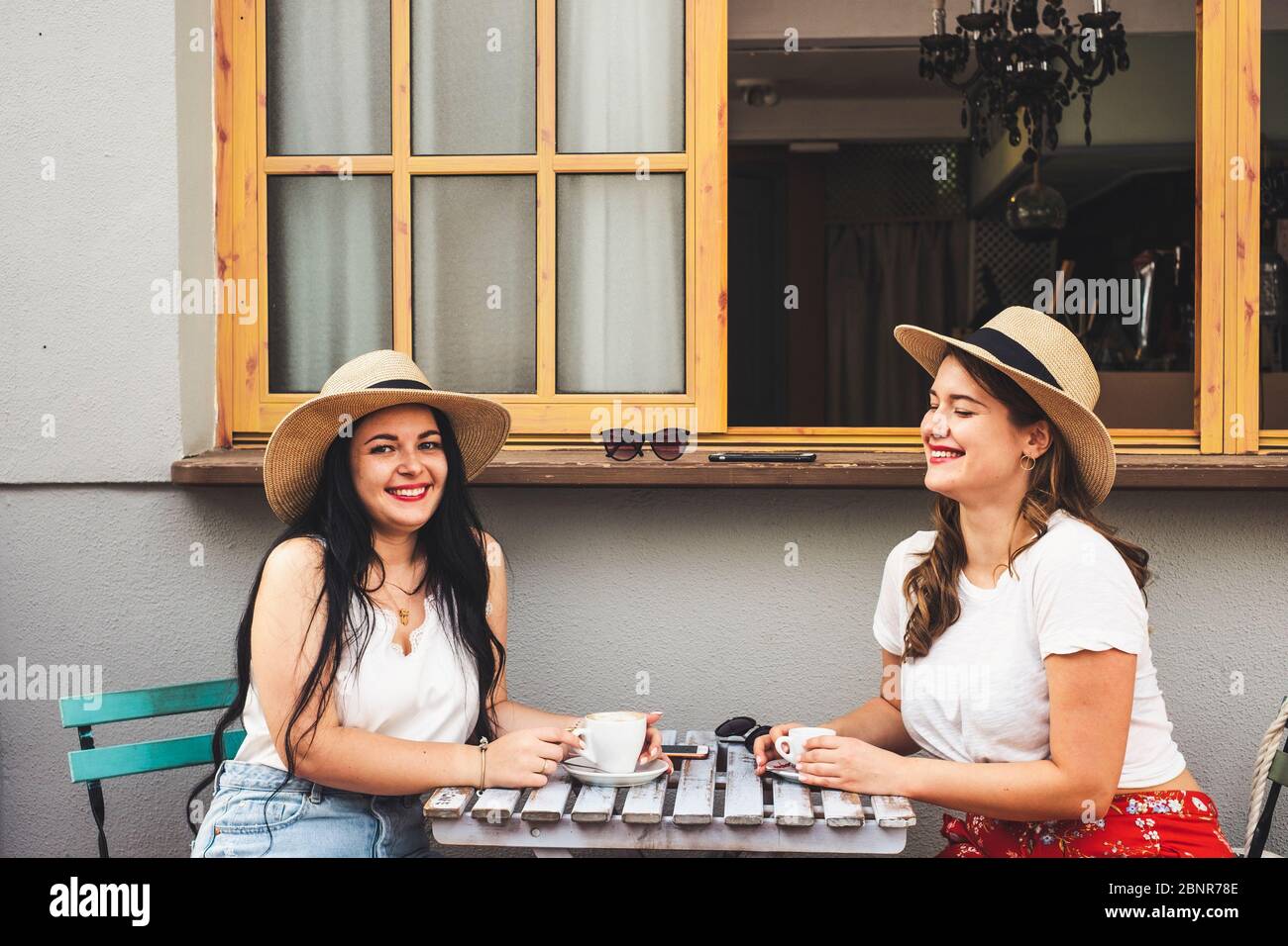 Glücklich schöne fröhliche paar Menschen junge Frauen Freunde genießen Kaffee und Cappuccino an der Fledermaus sitzen auf einem Tisch im Freien - trendige Mädchen und Freundschaft Konzept in der Freizeit Stockfoto