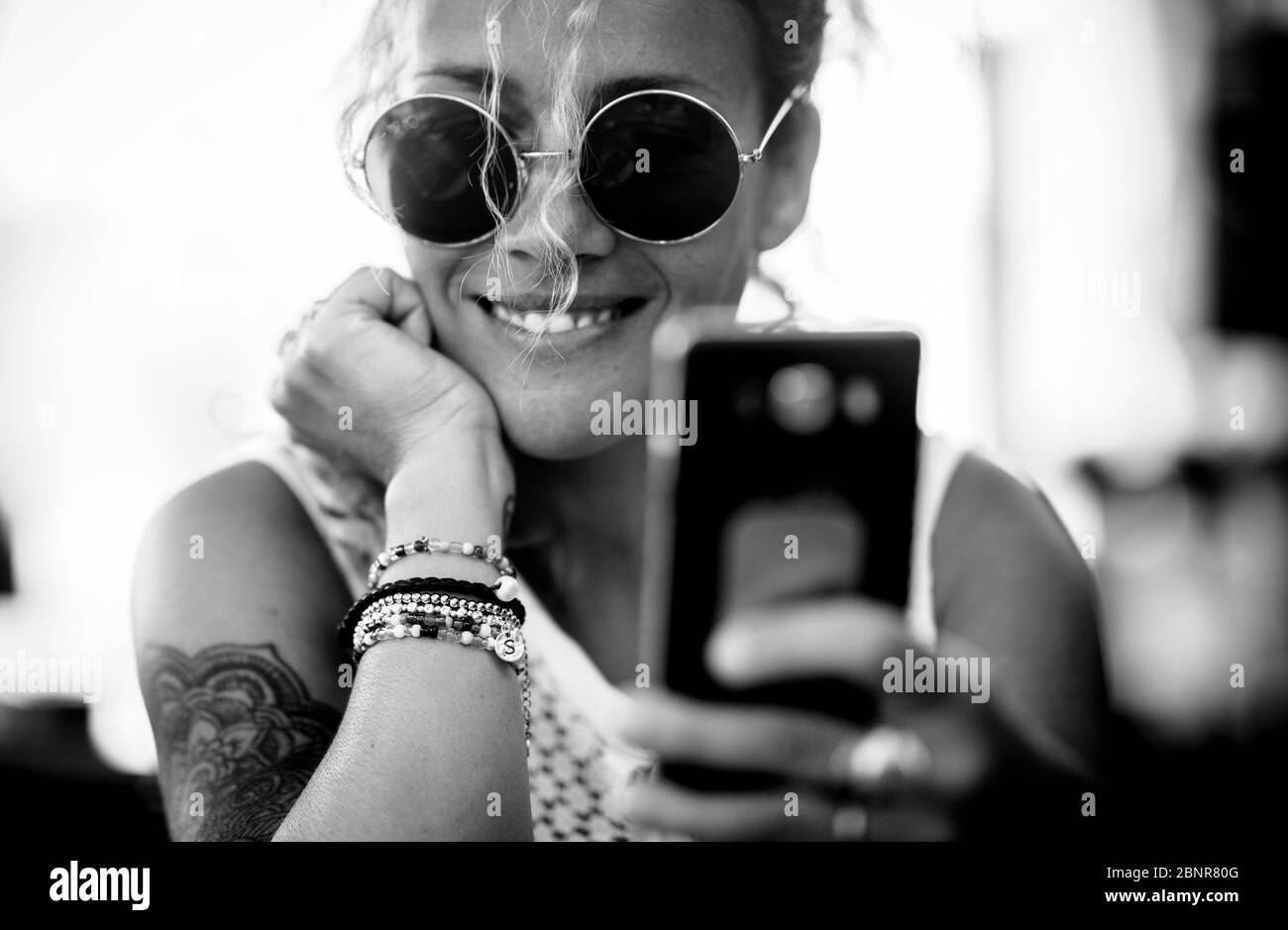 Schwarz-weiß schöne Erwachsene kaukasischen alernative trendy Frau Porträt - fröhlich und lächeln Dame mit Tatto tun Selfie-Bild oder Videoanruf mit Handy Stockfoto