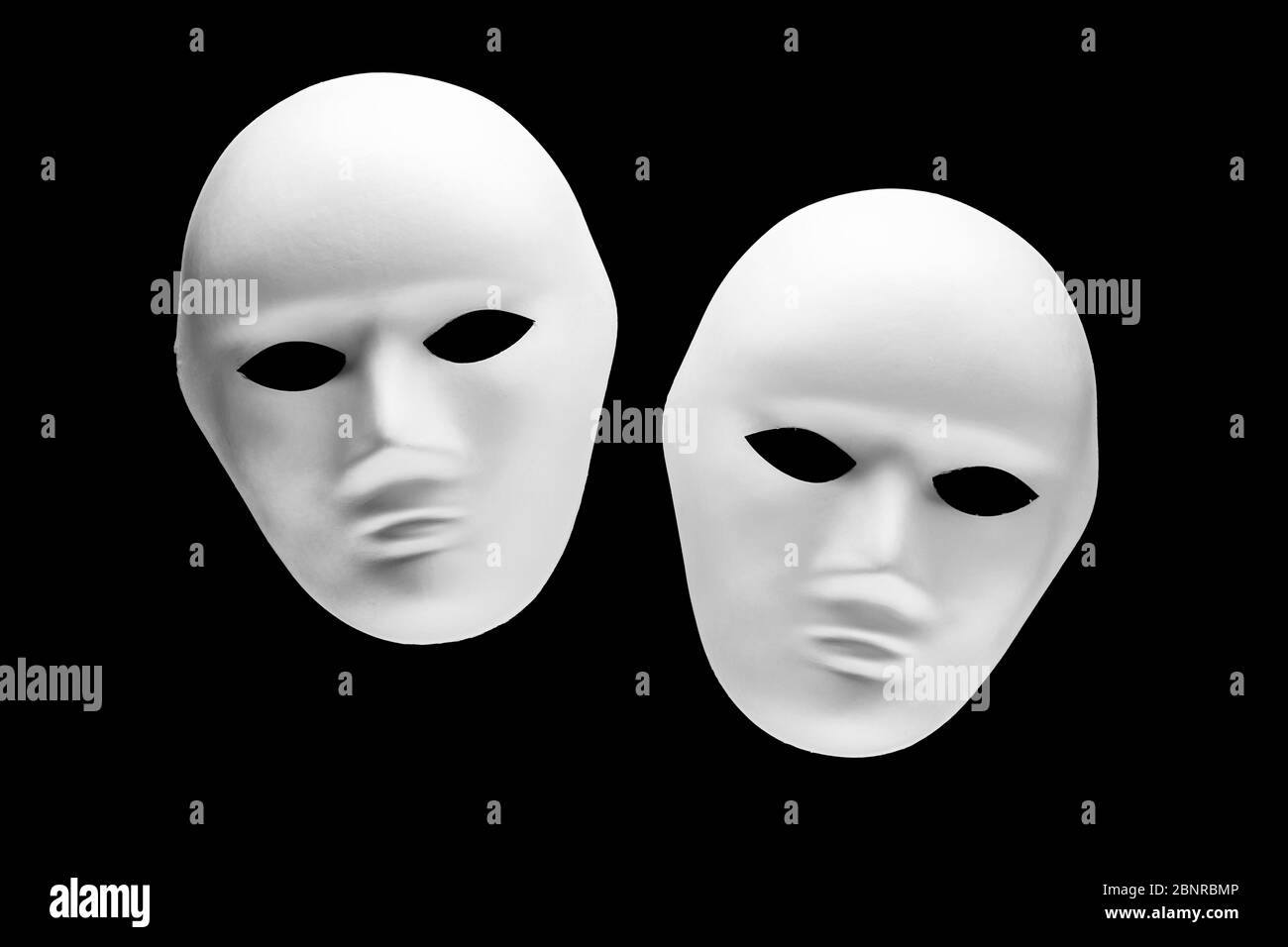 Zwei menschliche Gesichtsmasken isoliert auf schwarzem Hintergrund. Konzept der psychologischen Identität oder Persönlichkeitsstörung Stockfoto