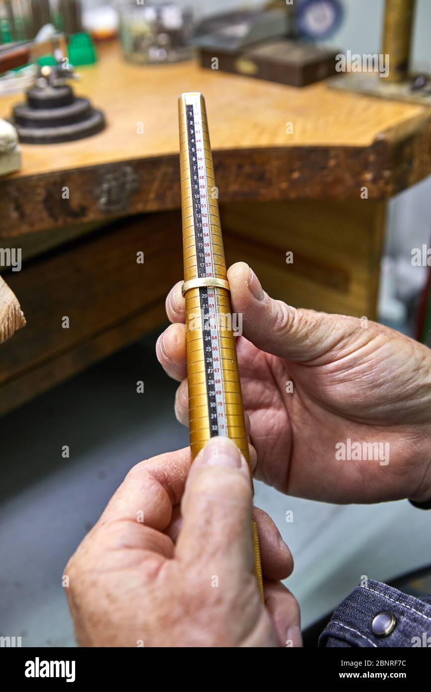 Schmuckherstellung. Der Juwelier macht einen goldenen Ring. Der Prozess der Messung des Rings an einer speziellen dimensionalen Schraube. Detailaufnahme mit geringer Fieltiefe Stockfoto