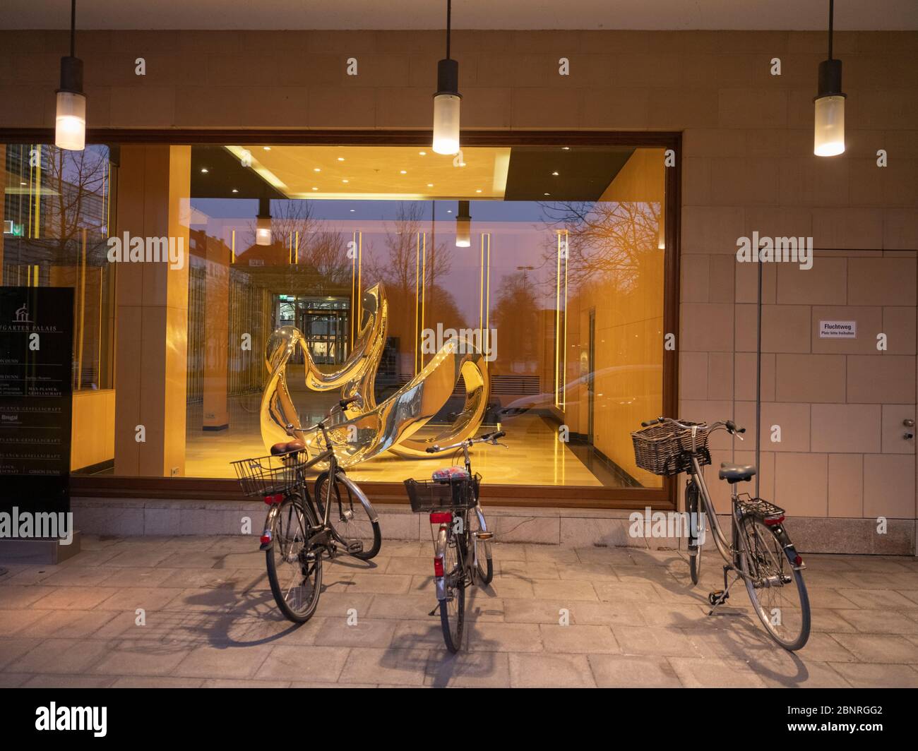 Schaufenster mit Kunstgegenstand und geparkten Fahrrädern in der Abenddämmerung Stockfoto