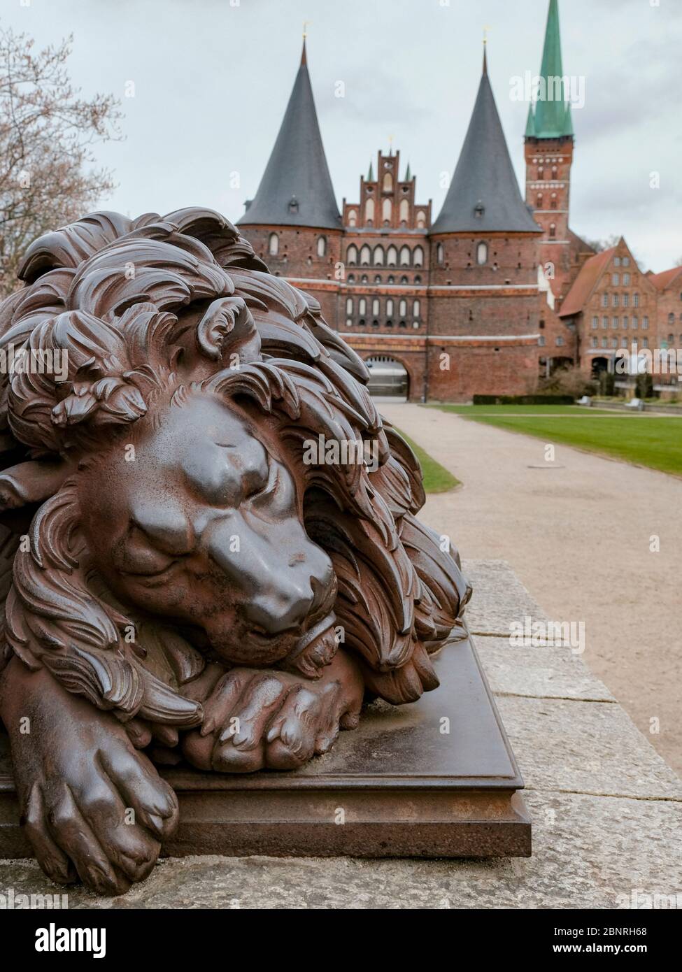 Skulptur eines schlafenden Löwen vor dem Lübecker Holstentor, als Symbol für den Stillstand in der Tourismusbranche. Stockfoto