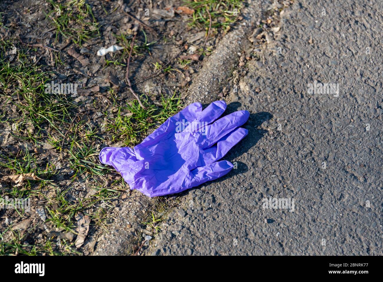 Ein Schutzhandschuh liegt auf einem Asphaltweg, Corona, Corona Pandemie, Corona-Epidemie, symbolisches Bild Stockfoto