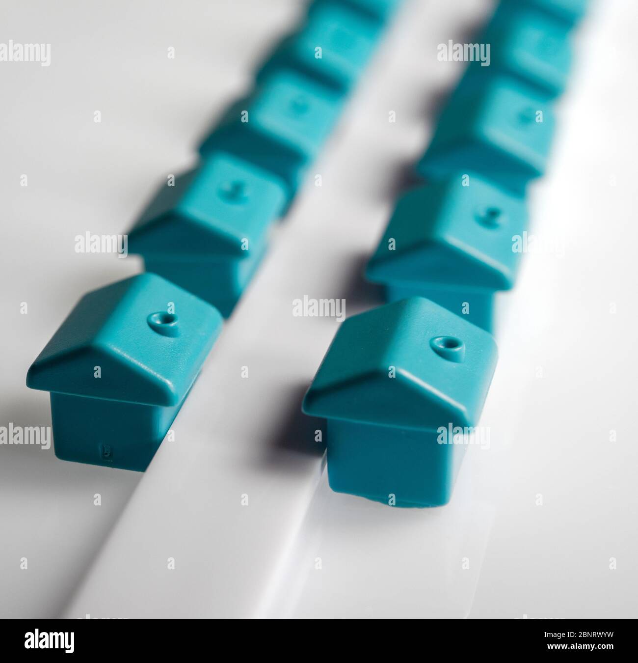 Wohnungsmarkt Konzept, kleine blaue Häuser auf weißem Hintergrund Stockfoto