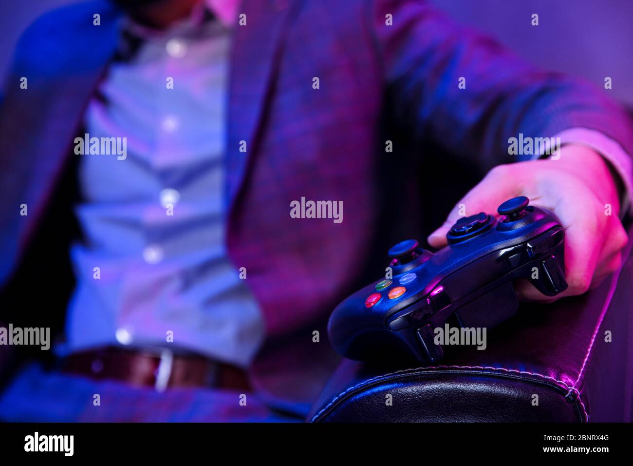 Eleganter Mann hält Gaming-Controller und spielt Spiele Stockfoto