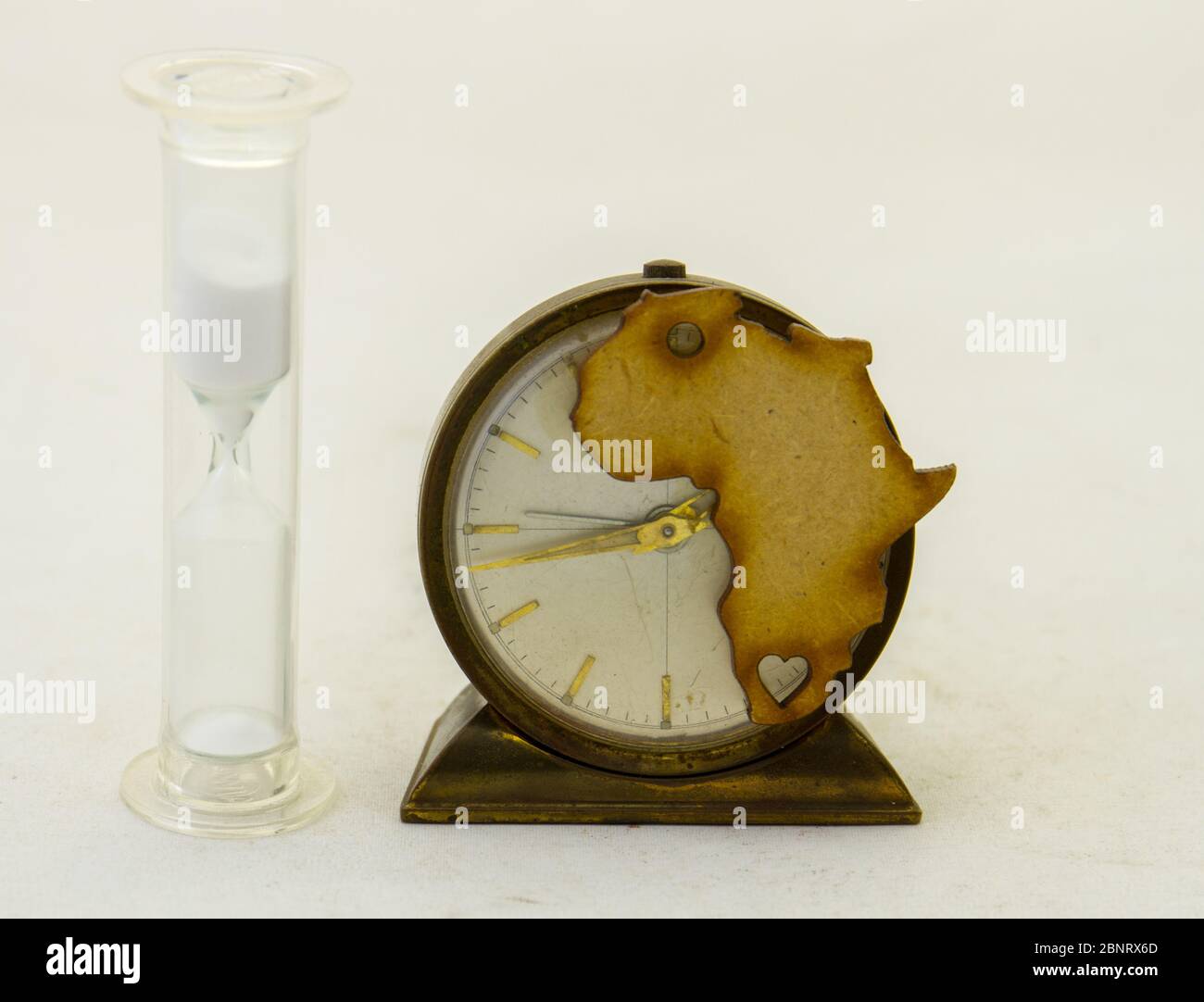 Die Form Afrikas auf einer alten Uhr und einer Sanduhr isoliert auf einem klaren Hintergrundbild mit Kopierraum Stockfoto