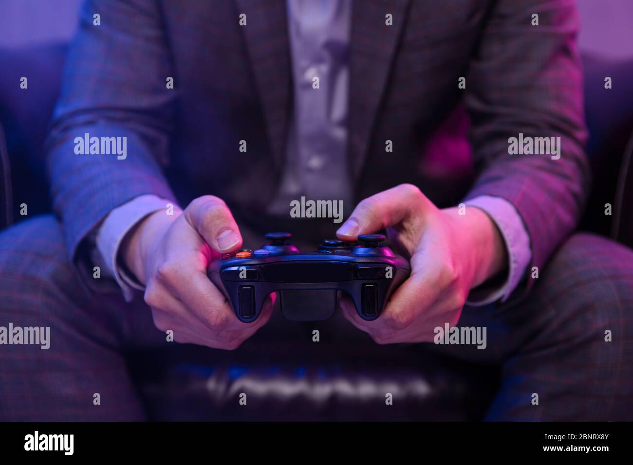 Eleganter Mann hält Gaming-Controller und spielt Spiele Stockfoto