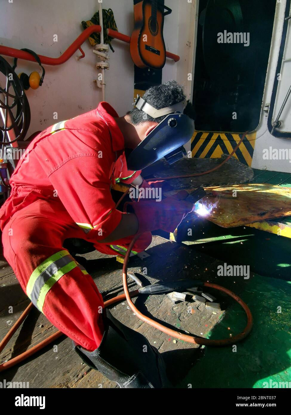 Schweißer fertigt Metallplatte auf Deck Stockfoto