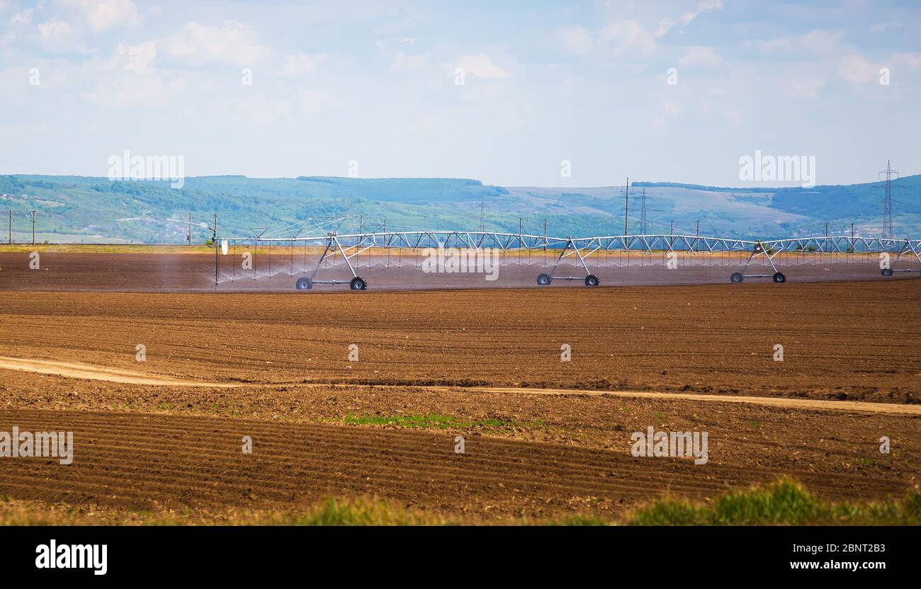 Bewässerungssystem vor Ort. Ein Bewässerungsdrehpunkt Bewässerung eines Feldes. Stockfoto