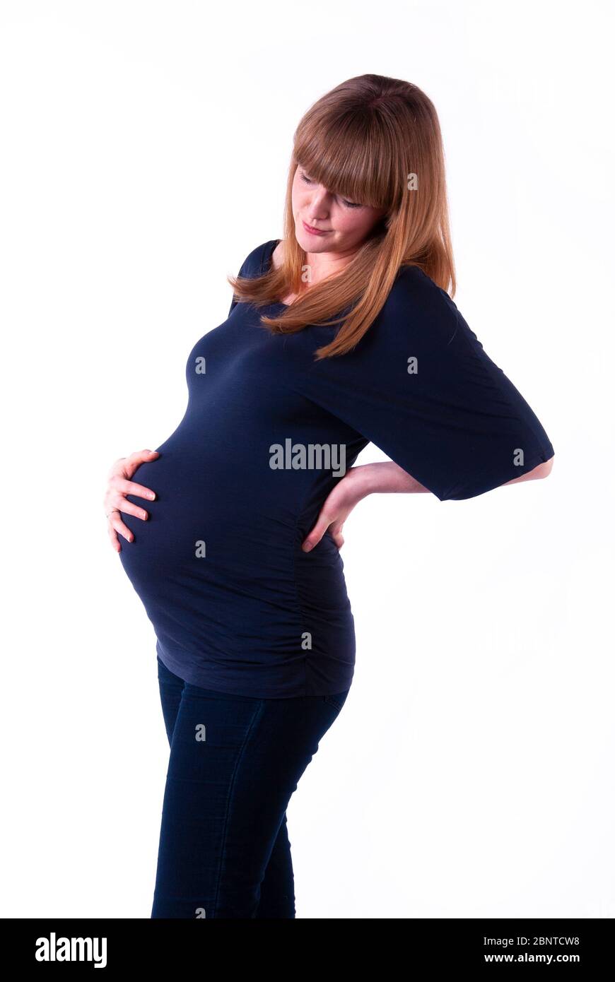Eine junge schwangere Frau mit Rückenschmerzen. Stockfoto