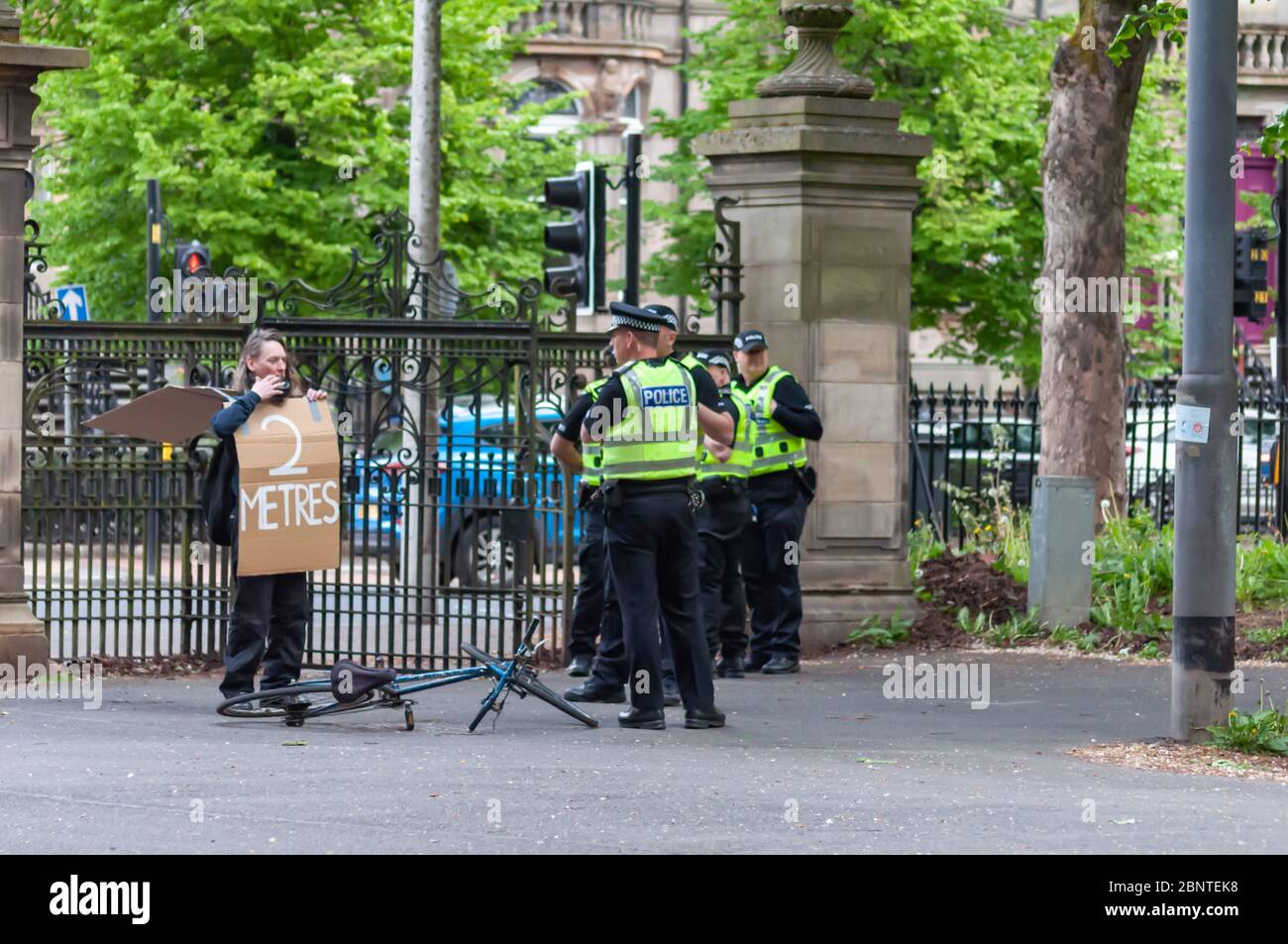 Glasgow, Schottland, Großbritannien. Mai 2020. Ein einiger Protestler kommt mit einem Schild aus Pappe auf seinem Fahrrad an und sagt 2 Meter 2 weit und wird von Polizisten der Polizei Schottlands angesprochen, die ihm später erlaubten, auf seinem Weg zu gehen. Die Anti-Lockdown-Massenversammlung im Queen’s Park wurde von der Protestgruppe UK Freedom Movement organisiert, die Anti-Lockdown-Veranstaltungen in ganz Großbritannien plante, indem sie Plakate in sozialen Medien herausgab, die die Versammlungen ermutigten. Die Polizei Schottland sagt der Öffentlichkeit, dass sie nicht an den Veranstaltungen teilnehmen soll. Kredit: Skully/Alamy Live News Stockfoto