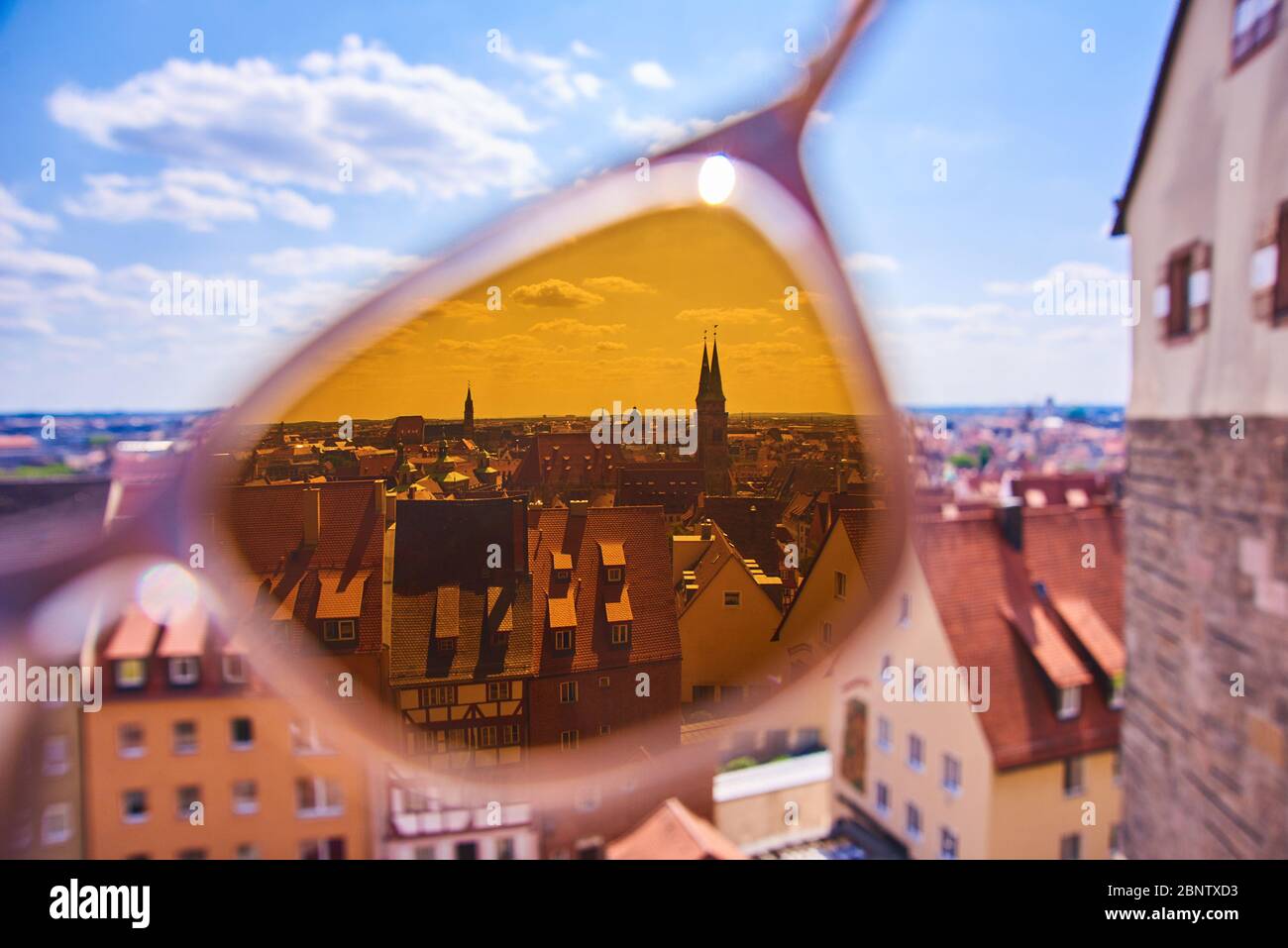 Blick durch gelbe Sonnenbrille City View, auf Linse mit verschwommenem Hintergrund fokussiert. Sehenswürdigkeiten der europäischen Altstadt Stockfoto