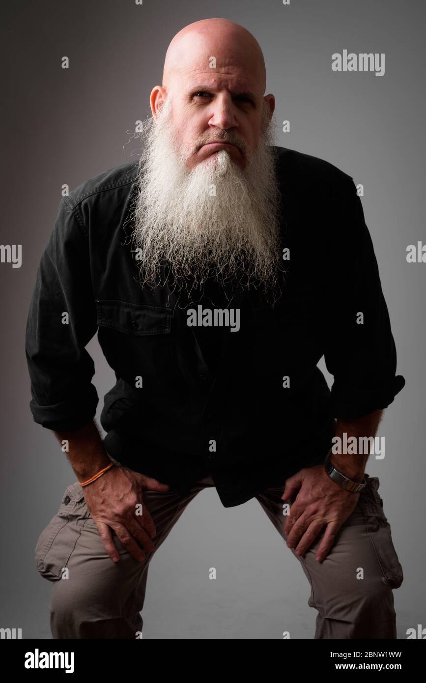 Gestresst reifen kahlen Mann mit langem Bart suchen wütend, während lehnen nach vorne Stockfoto