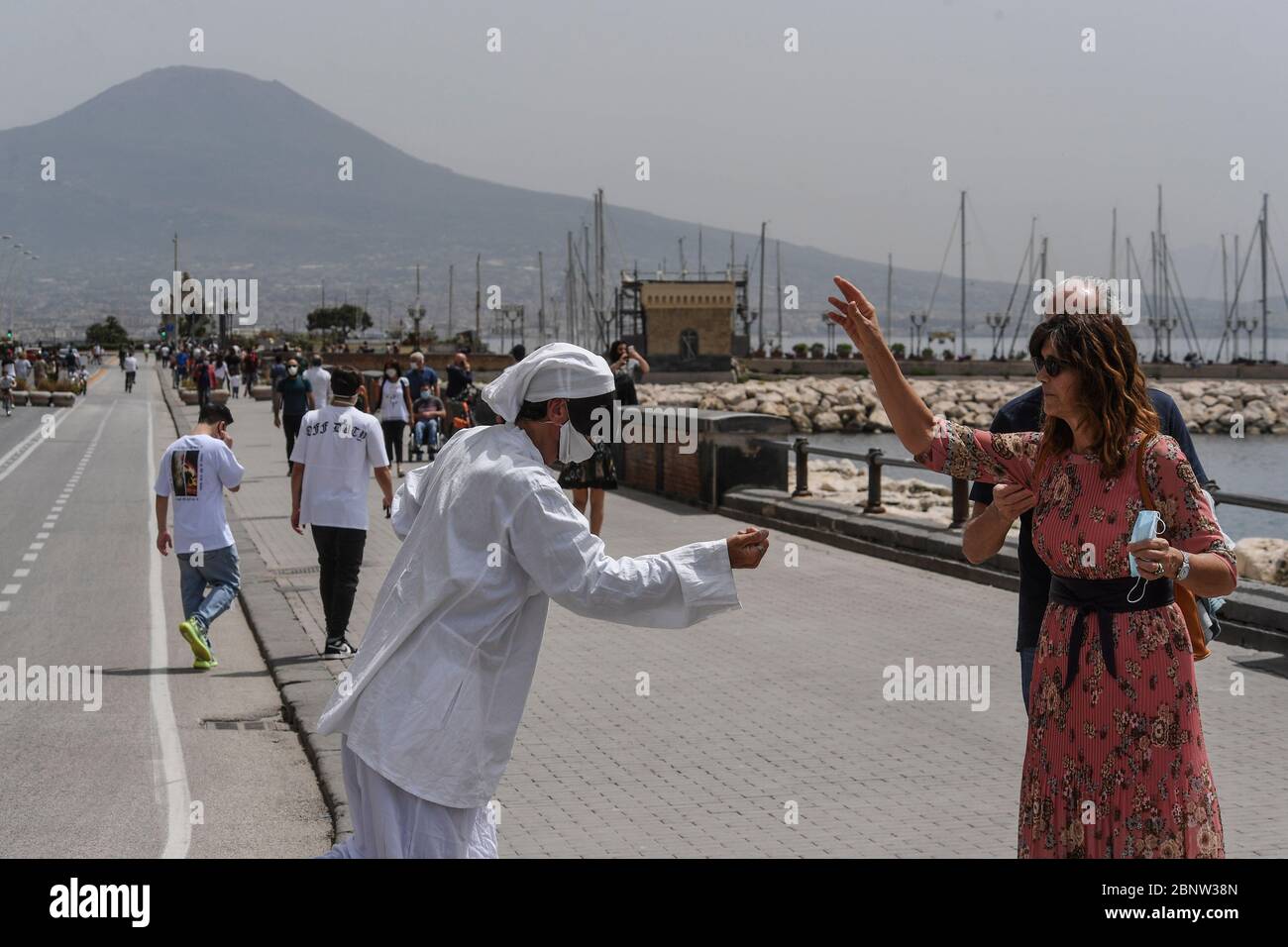 Ein neapolitanischer Künstler, gekleidet als Punch (Pulcinella), Maske der neapolitanischen Theatertradition, tritt unter den Menschen an der Küste von Neapel auf. Italien beginnt mit dem Ende einer nationalen Blockade aufgrund der Ausbreitung der Coronavirus-Krankheit. Stockfoto