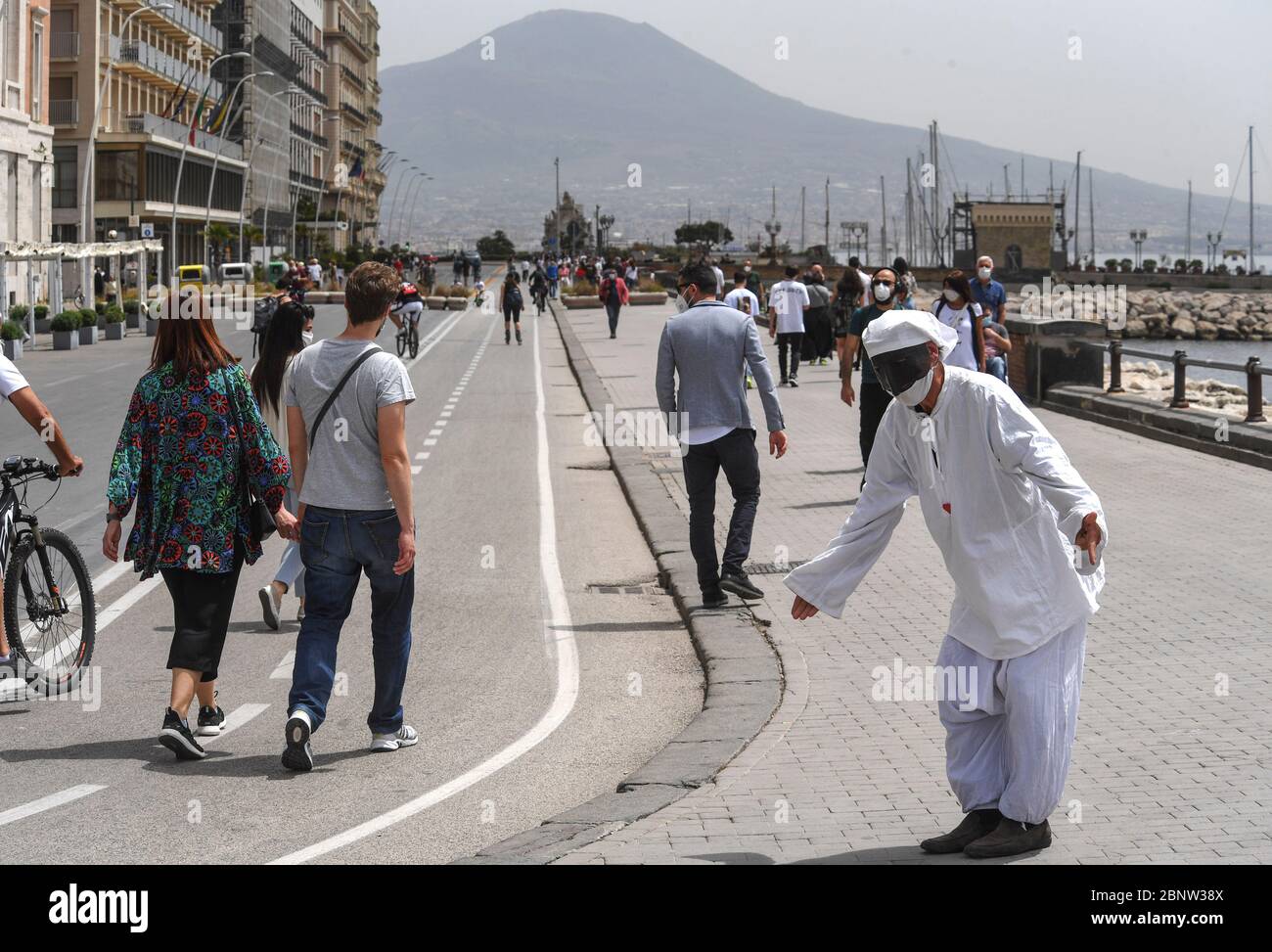 Ein neapolitanischer Künstler, gekleidet als Punch (Pulcinella), Maske der neapolitanischen Theatertradition, tritt unter den Menschen an der Küste von Neapel auf. Italien beginnt mit dem Ende einer nationalen Blockade aufgrund der Ausbreitung der Coronavirus-Krankheit. Stockfoto