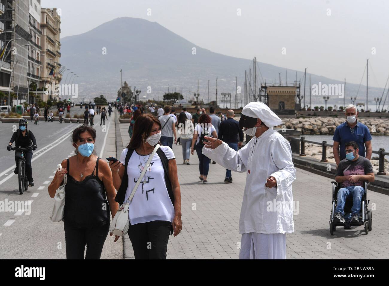 Ein neapolitanischer Künstler, gekleidet als Punch (Pulcinella), Maske der neapolitanischen Theatertradition, tritt unter den Menschen an der Küste von Neapel auf. Italien beginnt mit dem Ende einer nationalen Blockade aufgrund der Ausbreitung der Coronavirus-Krankheit. Stockfoto