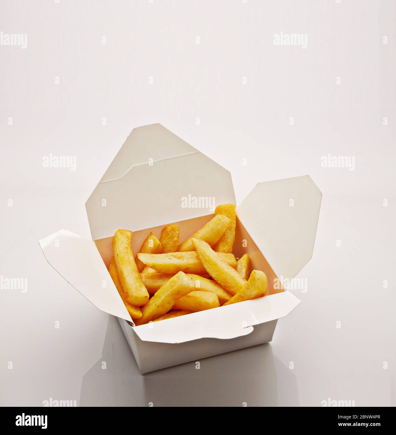 Aufnahme von pommes frites in Papierschachtel auf weißem Hintergrund Stockfoto