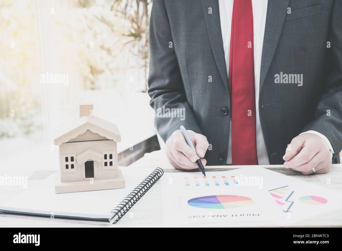 Ein Immobilienentwickler oder Immobilienmakler, der an seinem Schreibtisch arbeitet und den aktuellen Immobilienmarkt mit Diagrammen und Grafiken berechnet oder analysiert. Stockfoto