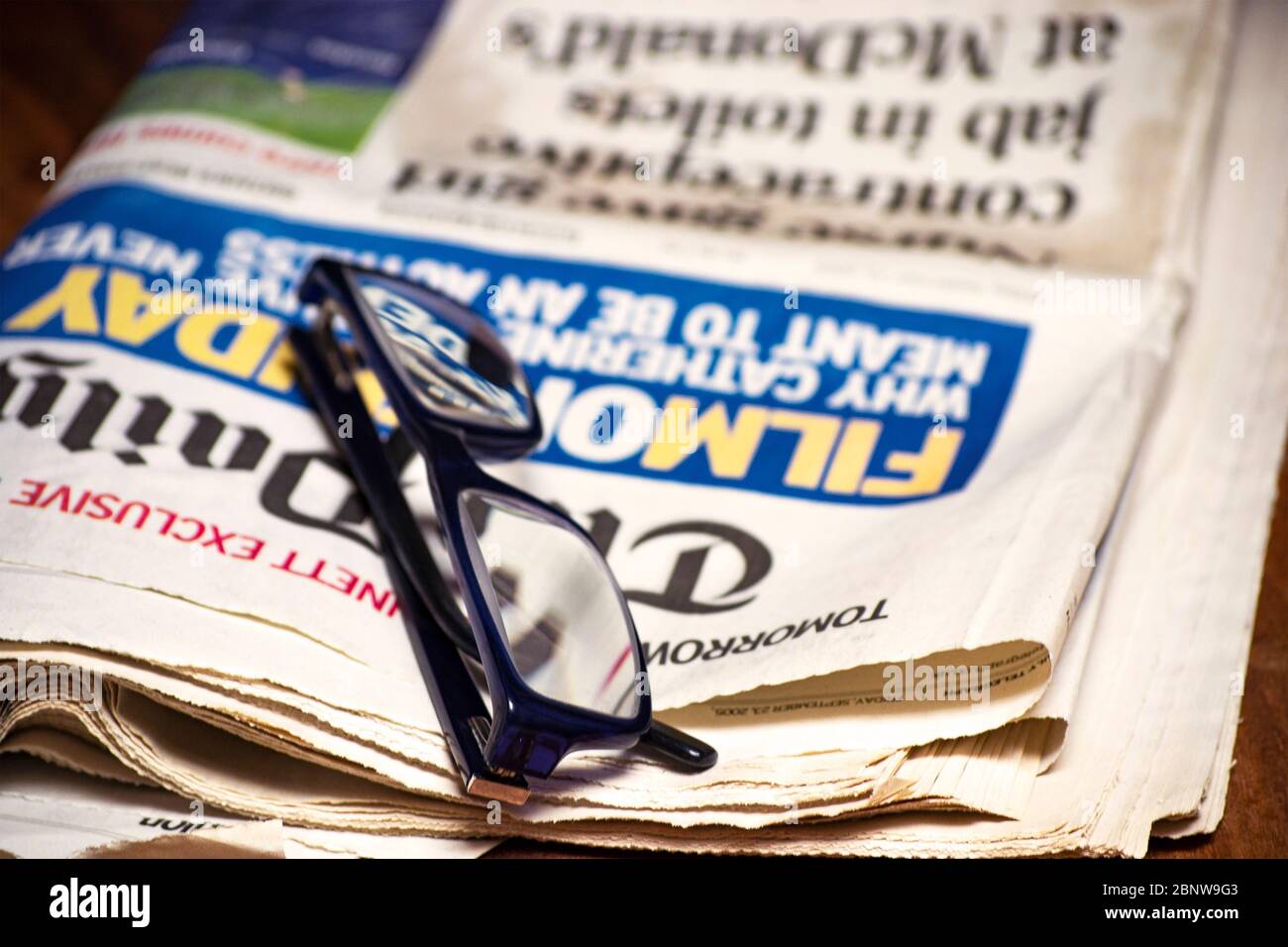 Gefaltete Zeitung mit einem Paar blauer Lesebrille darauf. Kostenlose Informationen und Pressekonzept Stockfoto