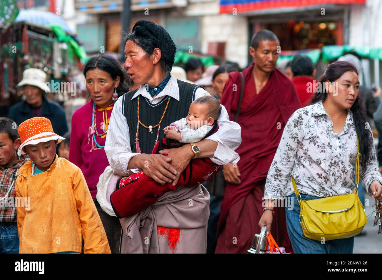 Vater mit Baby buddhistische Anhänger machen die Kora im Uhrzeigersinn Umrundung um Jokhang Tempel, Lhasa Tibet. Barkhor Platz im Herzen von Lhasa alt Stockfoto