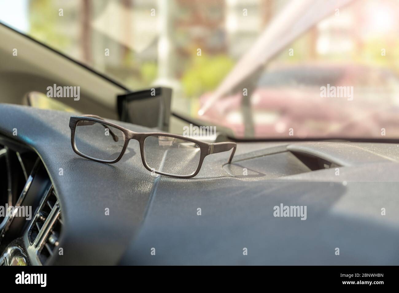 Brille liegt auf dem Armaturenbrett eines Autos. Die Notwendigkeit, eine Brille für Fahrer mit wenig Sicht zu tragen Stockfoto