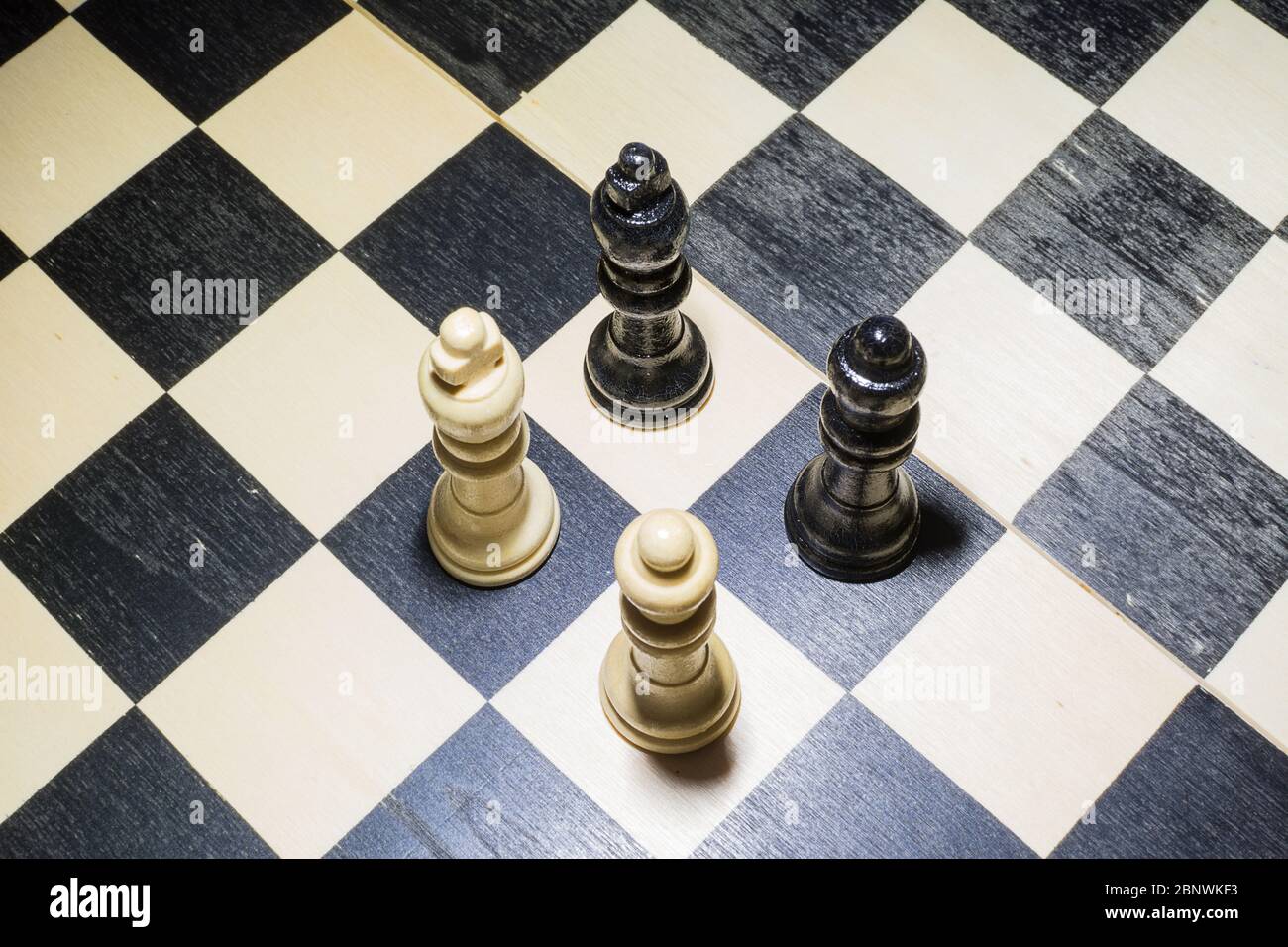 Das Schachbrett mit weißem König und Königin vor schwarzen im Konfrontationskonzept Stockfoto