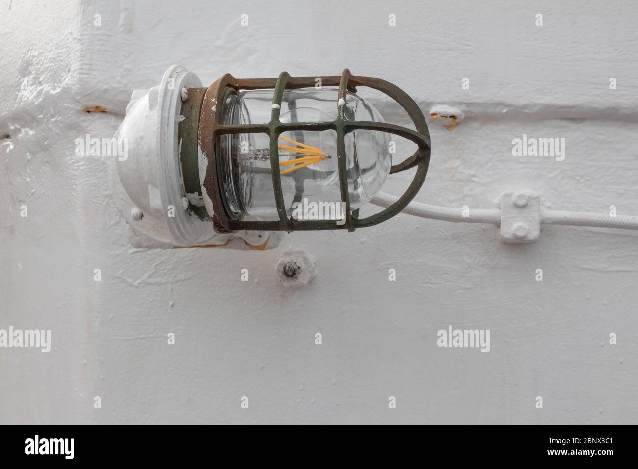 Nahaufnahme eines Schiffes Licht, grün und Rost Metall Lichtkäfig zum Schutz, weiß lackierten Hintergrund, horizontalen Aspekt Stockfoto