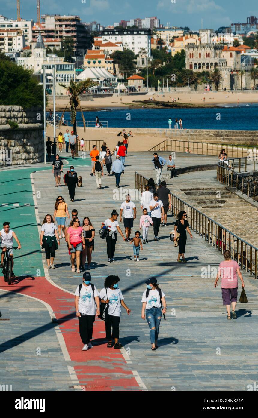 Blick auf die Menschen, die auf dem Meerespatal in Cascais, Portugal, spazieren. Einige tragen Gesichtsmasken während des Coronavirus Covid-19 Ausbruchs Stockfoto