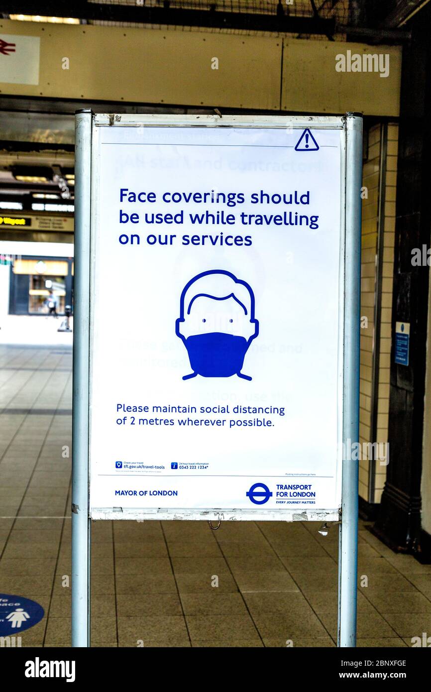 16. Mai 2020 London, Großbritannien - Schild, das die Menschen daran erinnert, Gesichtsmasken zu verwenden, während sie auf öffentlichen Verkehrsmitteln an der U-Bahnstation Embankment unterwegs sind, da die strengen Maßnahmen zur Sperrung der Coronavirus-Pandemie gelockert werden Stockfoto