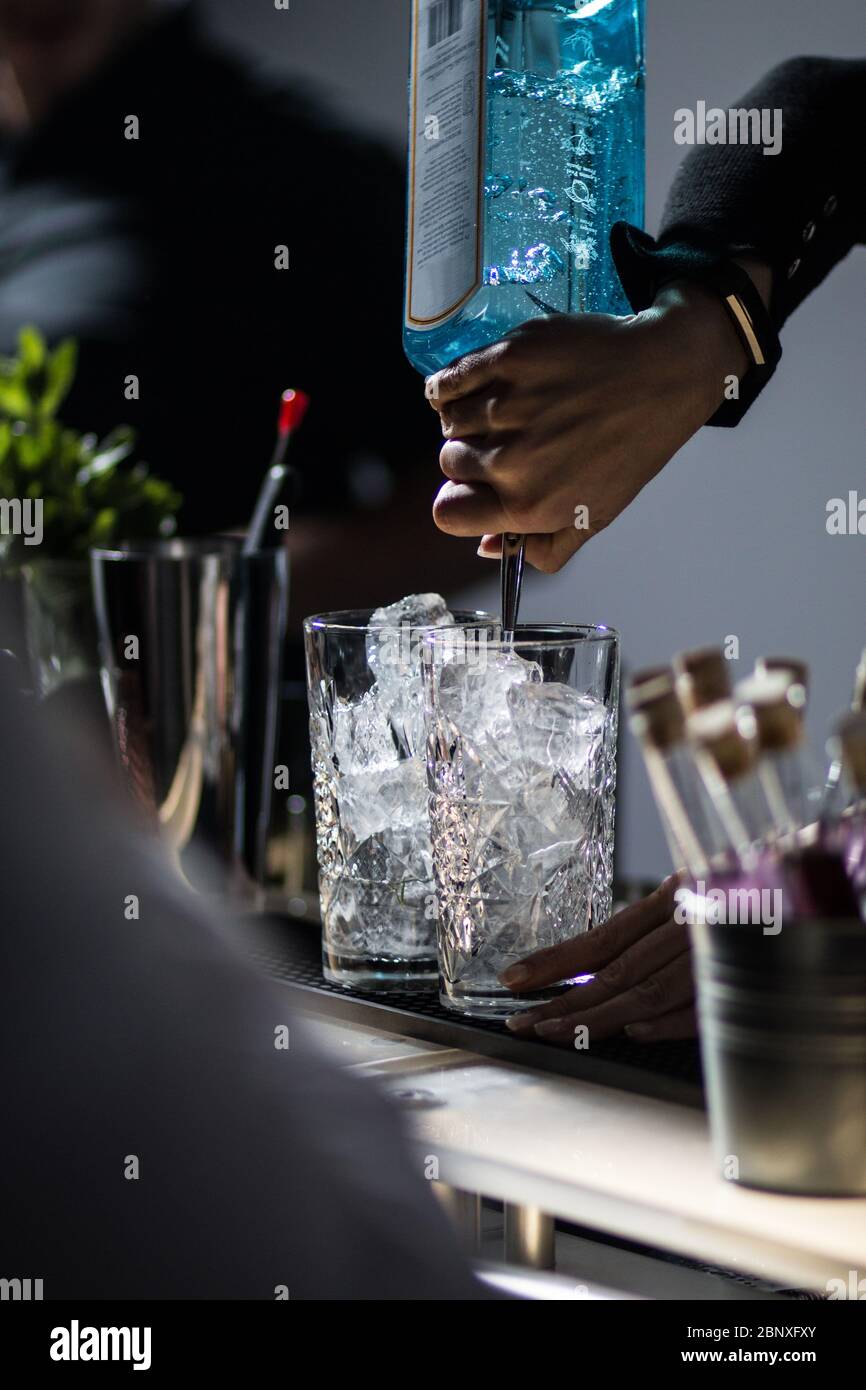 Cocktailmischung. Barkeeper gießt Gin aus. Mischen von Getränken auf Veranstaltung. Stockfoto