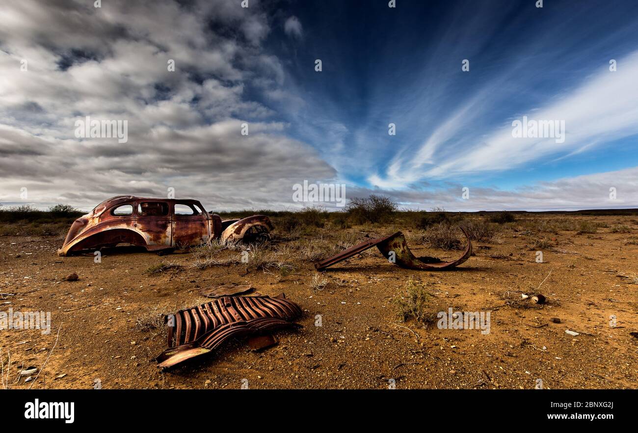 Altes Autowrack unter schönen Wolken mitten im Nirgendwo Stockfoto