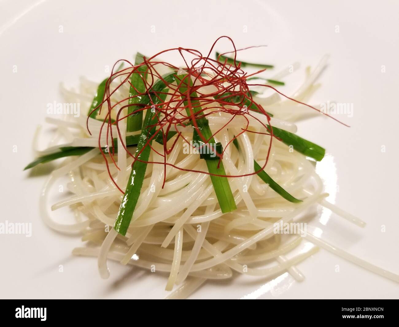 Bohnensprossen-Salat, bestehend aus gebratenen Bohnensprossen, Schnittlauch und straffer roter Paprika auf weißem Hintergrund Stockfoto