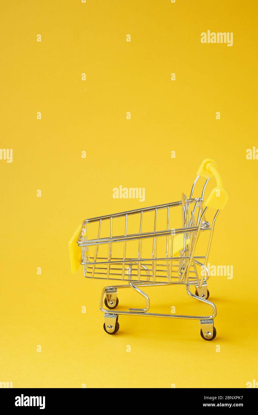 Ein Lebensmittelwagen auf gelbem Hintergrund.Online-Shopping. Ein Ort für Text. Stockfoto