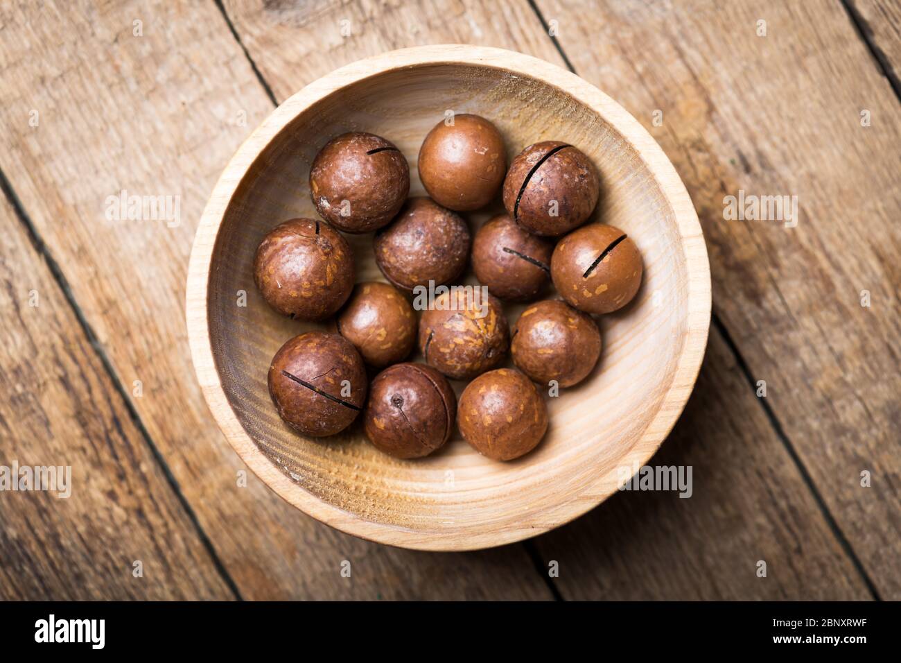 Getrocknete Bio-Macadamia-Nüsse in Holzschale Nahaufnahme. Makroaufnahmen in Studio. Food-Fotografie Stockfoto