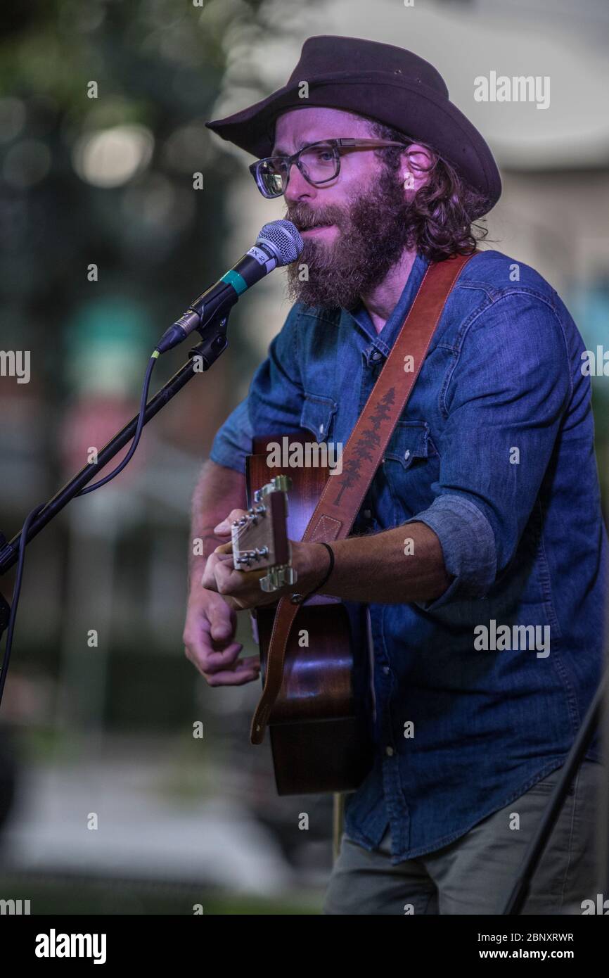 Bärtige Folksängerin beim Outdoor-Konzert. Singen und spielen akustische Gitarre. Stockfoto