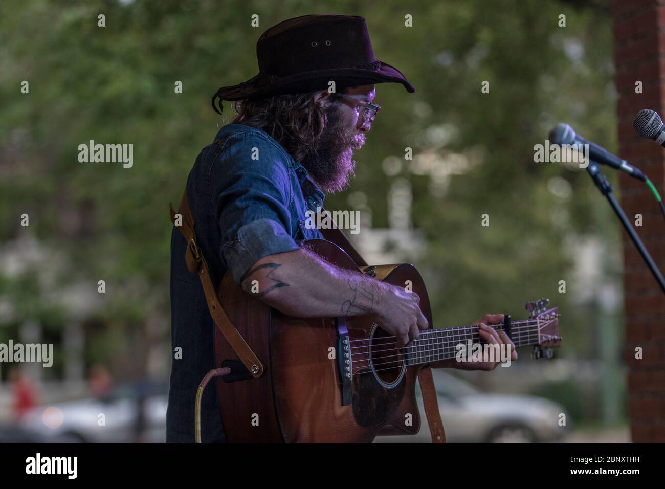 Bärtige Folksängerin beim Outdoor-Konzert. Singen und spielen akustische Gitarre. Stockfoto