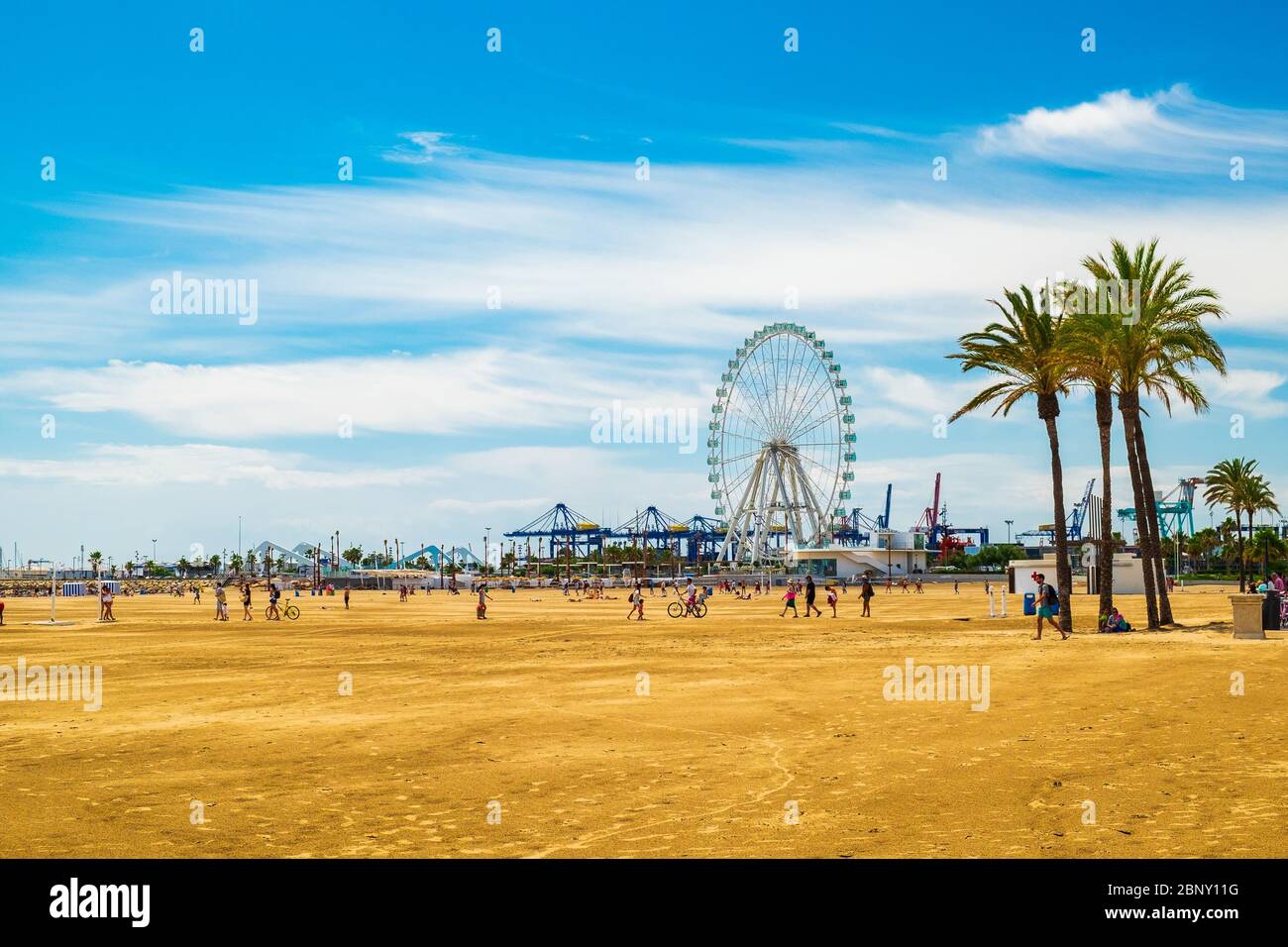 Valencia, Spanien: 14. Juni 2015 - Touristen und Einheimische gehen an den Strand, mit dem Riesenrad im Hintergrund Stockfoto