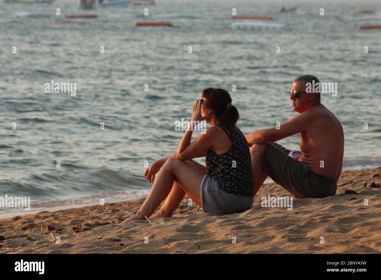 Ein paar ausländische Touristen, die am Strand sitzen. Stockfoto