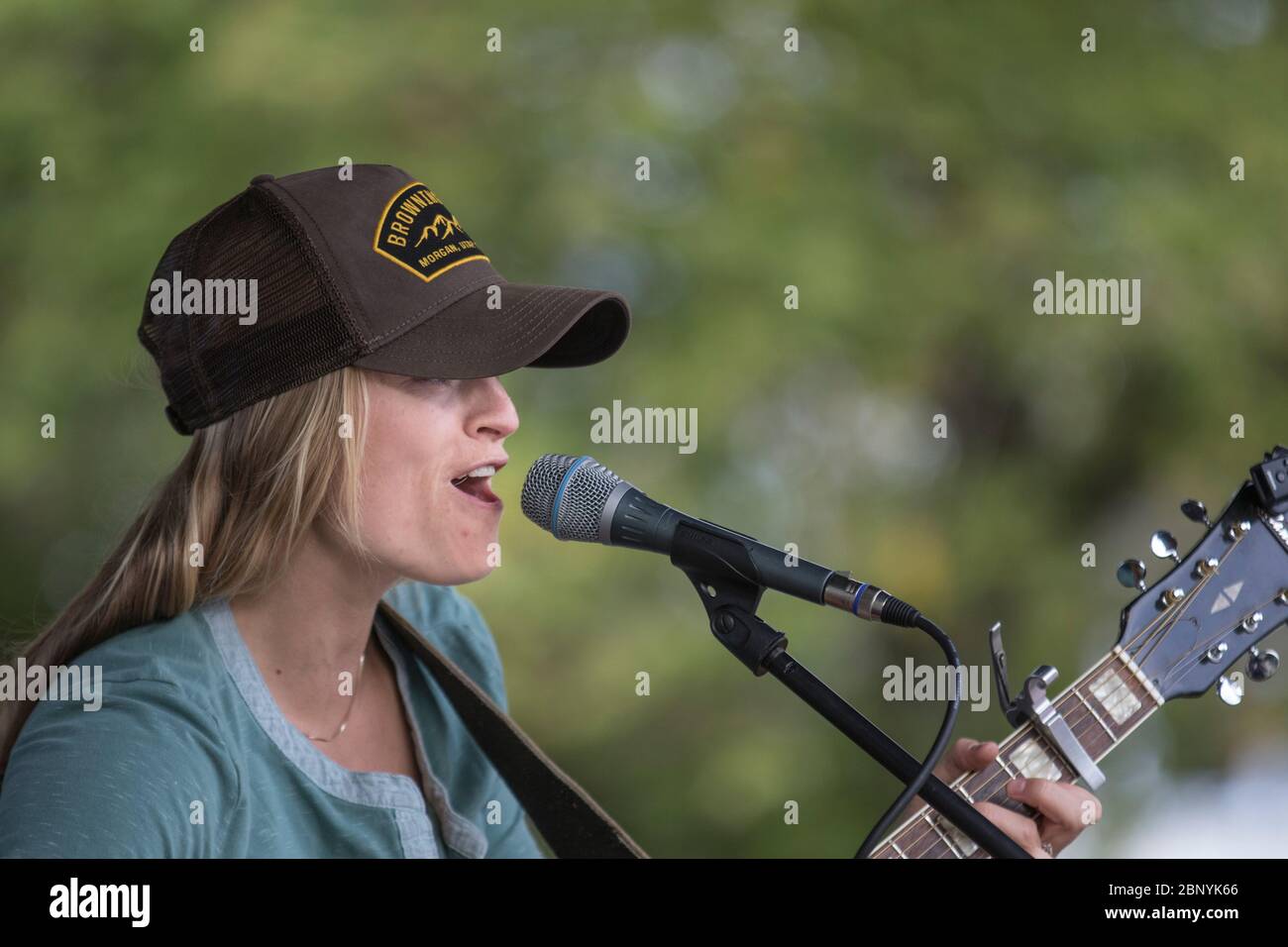 Hübsche, blonde, weibliche Folksängerin, die Gitarre spielt und beim Konzert im Freien singt. Stockfoto