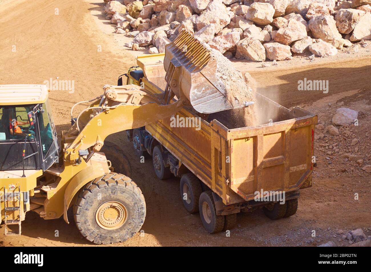 Frontlader lädt Stein in einen Muldenkipper. Stockfoto