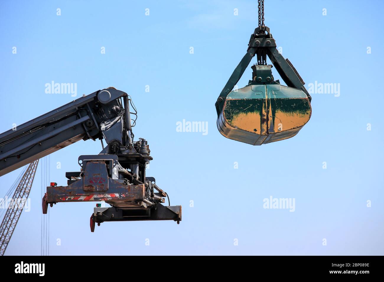 Großer Container-Handler und Clamshell-Bucket an einem lokalen Port. Stockfoto