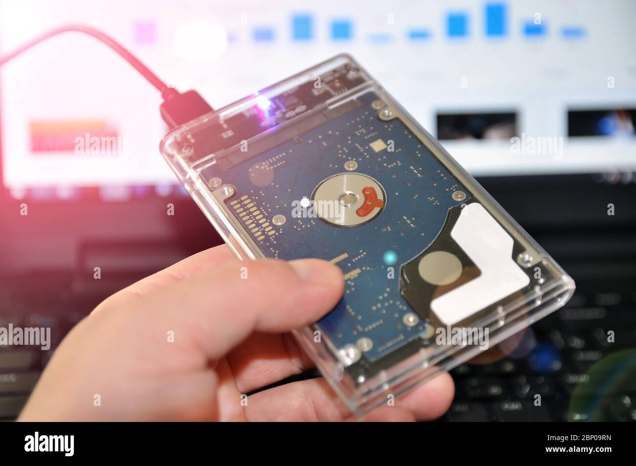 Eine externe oder tragbare Festplatte HDD, die an einen Laptop für die Datenübertragung oder Sicherung angeschlossen ist. Stockfoto