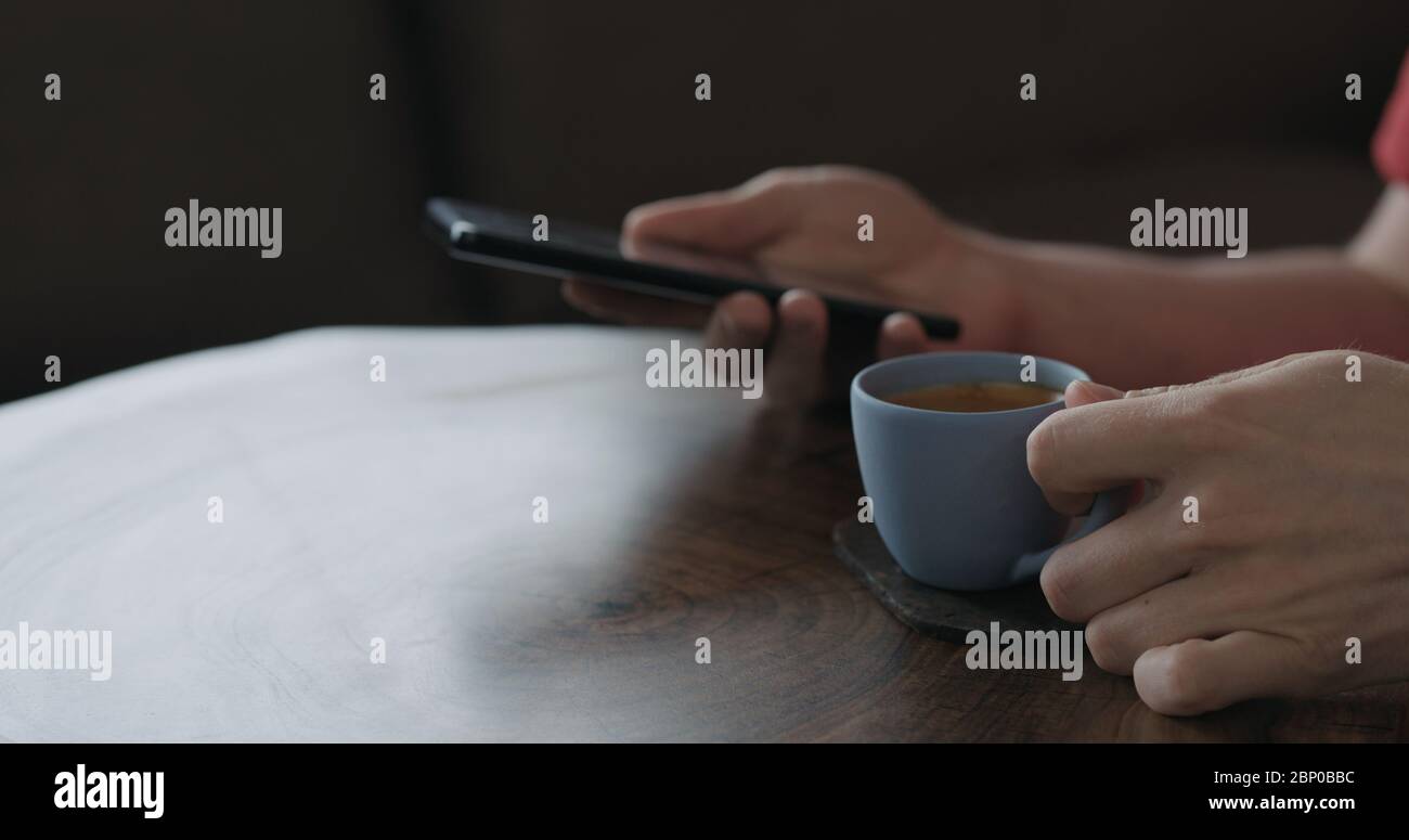 Nahaufnahme junger Mann benutzen Smartphone, während er am Tisch sitzt Und trinken Morgenkaffee Stockfoto