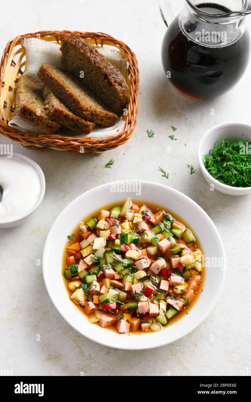 Sommer Okroshka Suppe mit Wurst, Gemüse und Kvass über hellem Stein Hintergrund. Traditionelles russisches Essen. Stockfoto