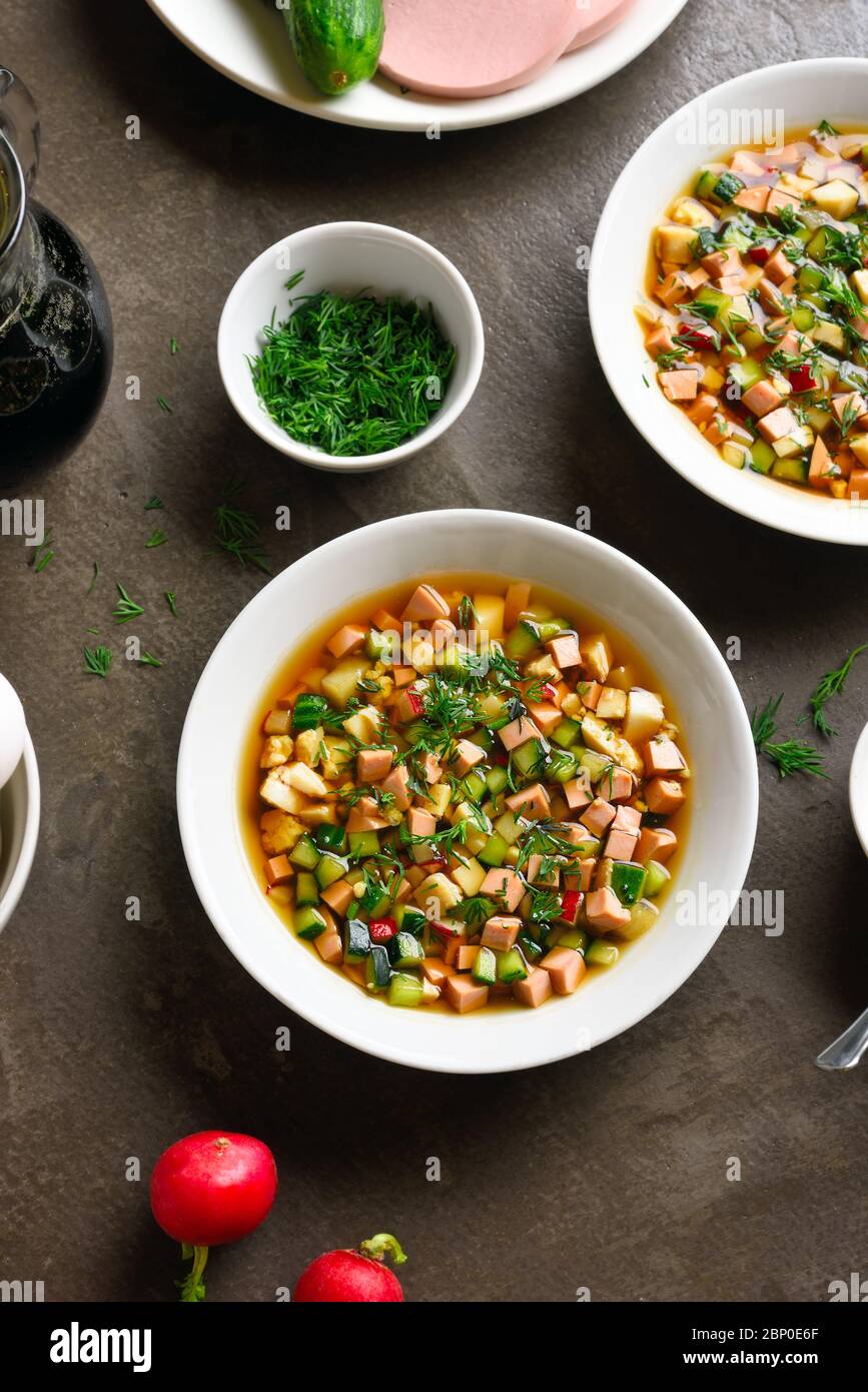 Traditionelle kalte russische Suppe Okroshka mit Wurst, Gemüse und Kvass auf braunem Stein Hintergrund. Leckeres Sommergericht zum Abendessen. Stockfoto