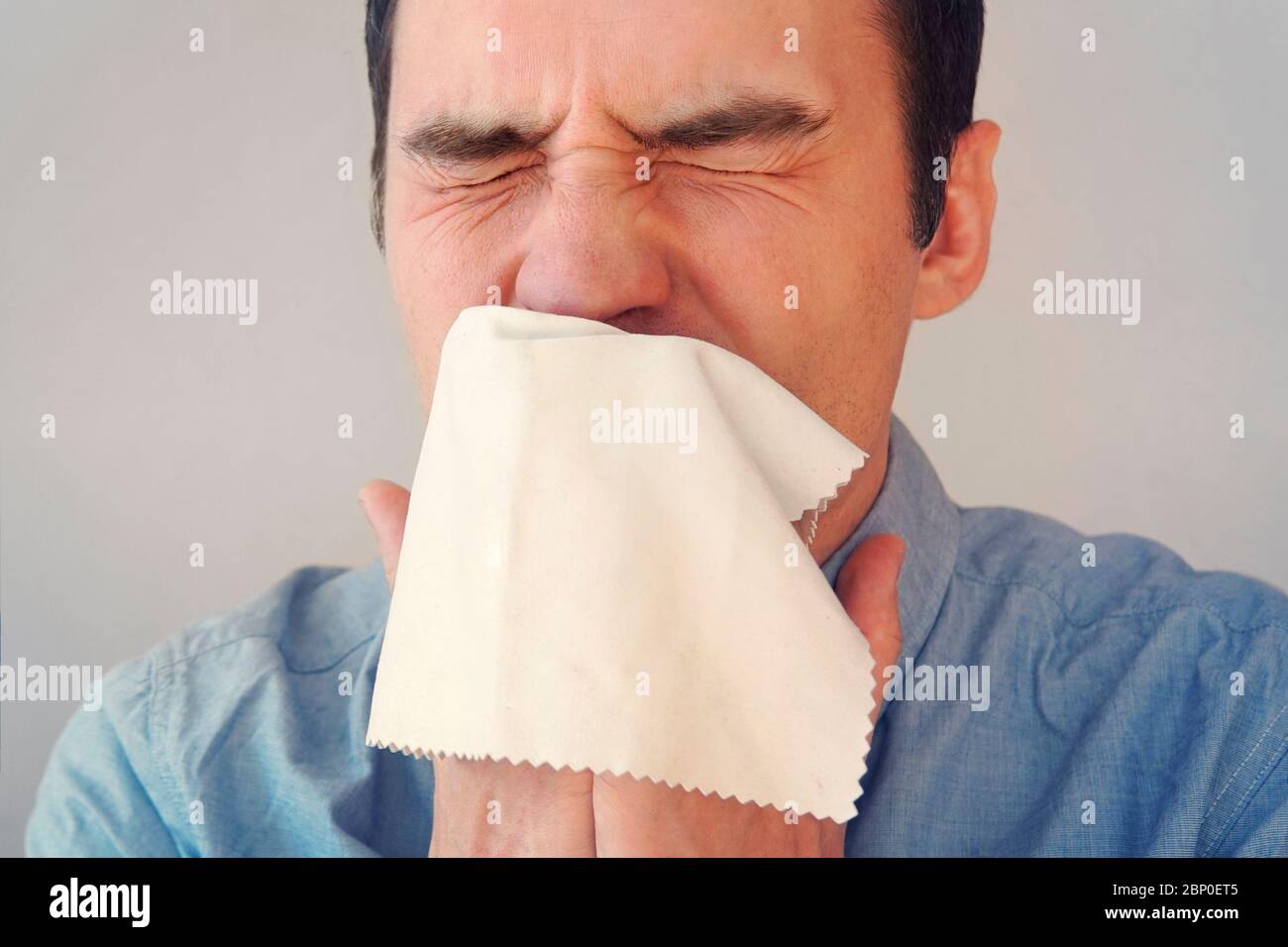 Geschäftsmann bläst seine Nase in einen Lappen. Junger Mann niest in Gewebe. Kerl ist krank, hat eine Erkältung oder allergische Reaktion. Coronavirus, Epidemie 2020, Krankheit Stockfoto