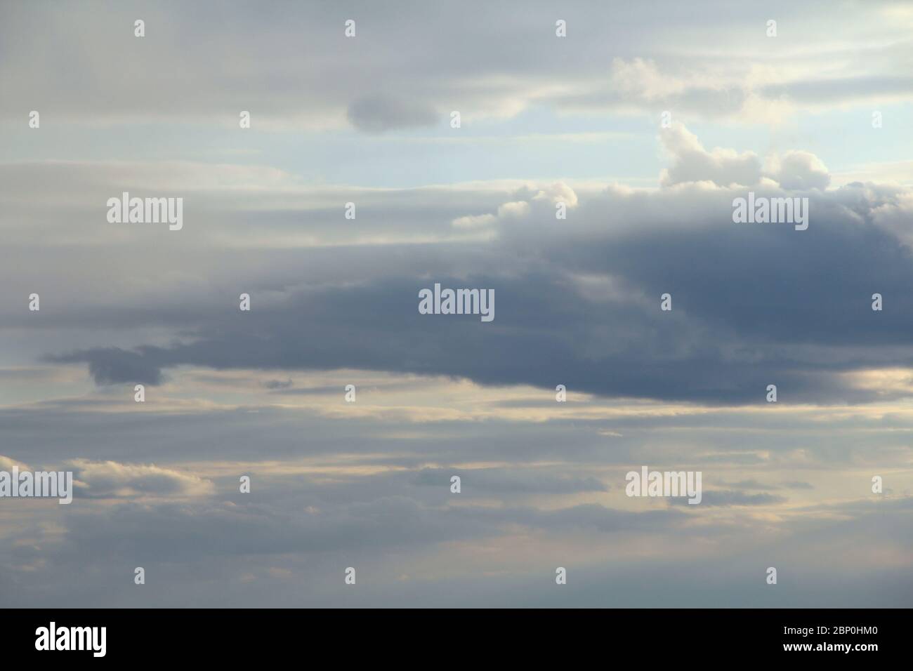 Wolken am blauen Himmel bei Sonnenuntergang oder Sonnenaufgang, die von der Sonne beleuchtet werden. Platz für Text und Design. Stockfoto