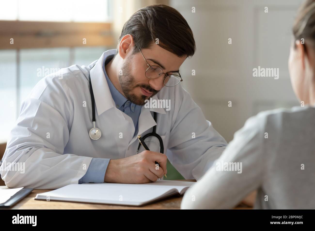Männlicher Arzt füllen Patienten Anamnese in medizinische Karte Stockfoto